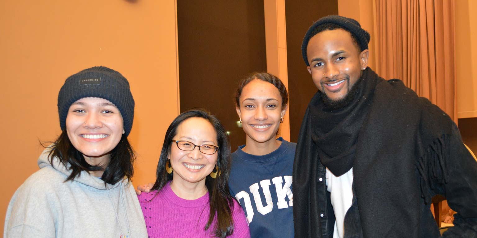 Three students and a professor smiling for a group picture
